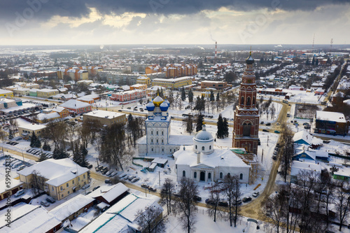 Scenic view from drone of temple complex of Cathedral of Archangel Michael and Church of Jerusalem Icon of Mother of God with Bronnitsy cityscape on background in winter, Russia..