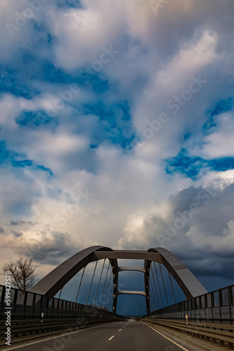 Winter landscape with dramatic clouds and a bridge on a sunny day near Plattling, Isar, Deggendorf, Bavaria, Germany © Martin Erdniss