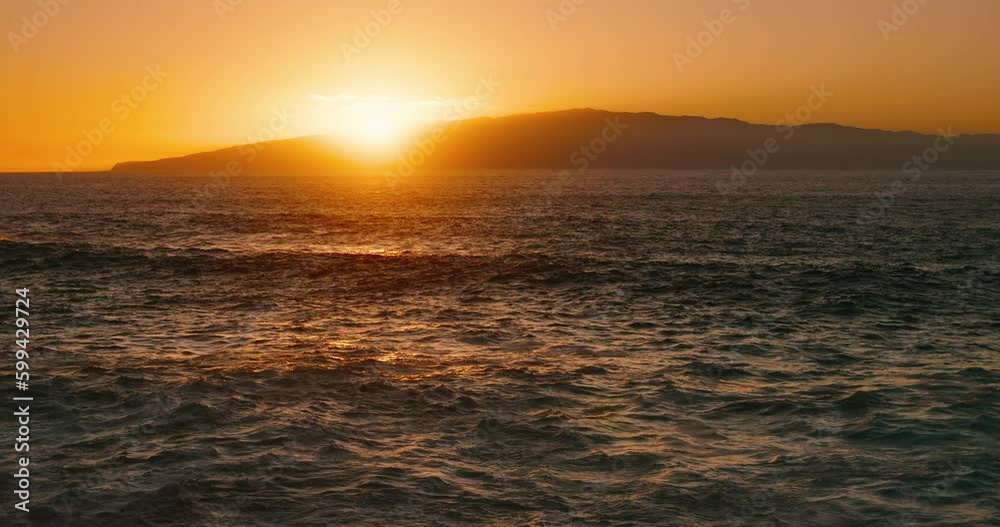 Golden sunset sky with warm reflection on ocean water surface and island La Gomera on horizon. Cinematic view from Tenerife. Golden sunset sky with warm reflection on ocean water surface and island La Gomera on horizon. Cinematic view from Tenerife.