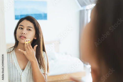 Woman applying makeup concept. Asian woman looking on mirror for applying make up  cosmetic on face by powder puff in morning routine. Cosmetic Make-up make woman more beautiful and self confidence.