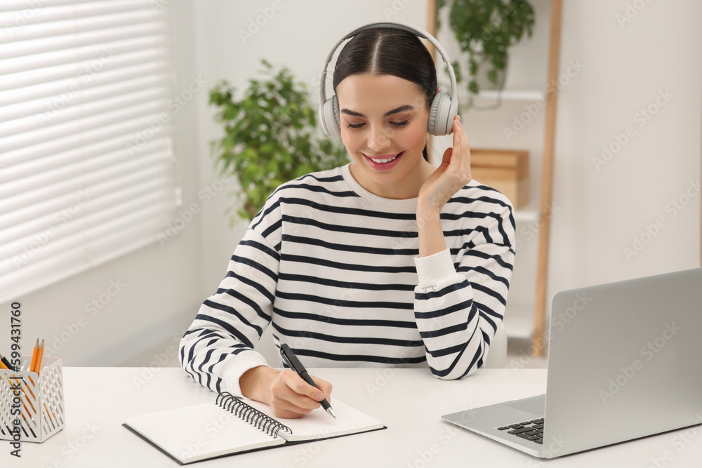 Obraz premium Online translation course. Student in headphones writing near laptop at home