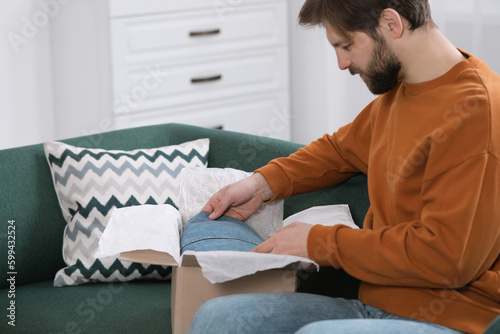 Man opening parcel at home. Internet shopping