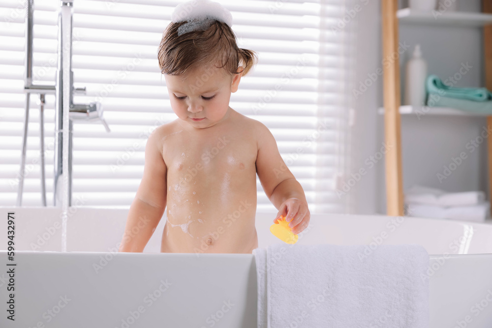 Cute little girl taking bath with toy indoors Cute little girl taking bath with toy indoors