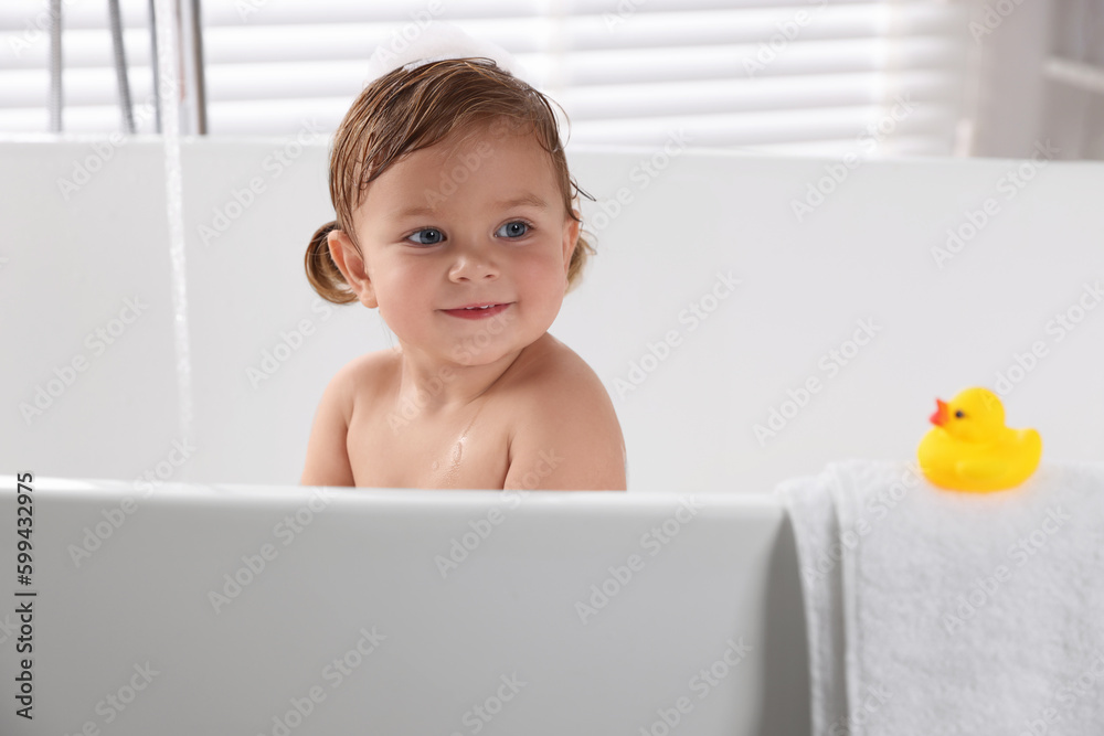 Cute little girl taking bath with toy indoors Cute little girl taking bath with toy indoors