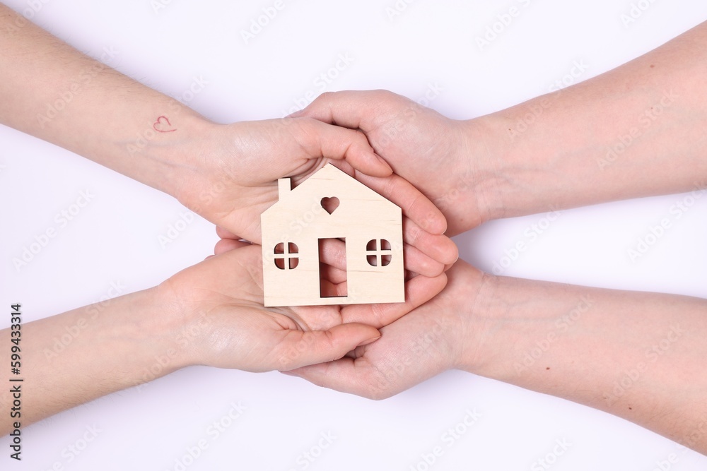 Home security concept. Couple holding house model on white background, top view