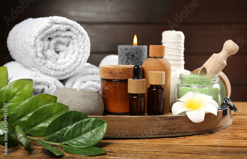Spa composition with herbal bags, cosmetics and towels on wooden table