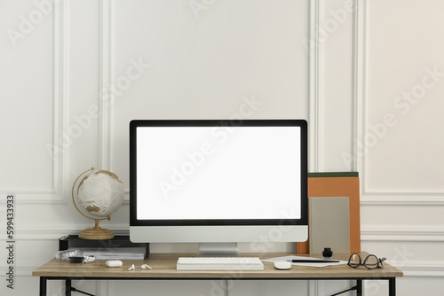 Stylish workspace with computer and stationery on wooden desk near white wall © New Africa