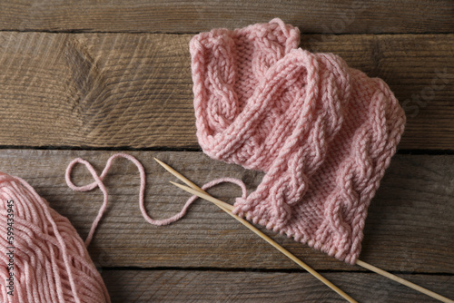 Soft pink woolen yarn, knitting and needles on wooden table, flat lay