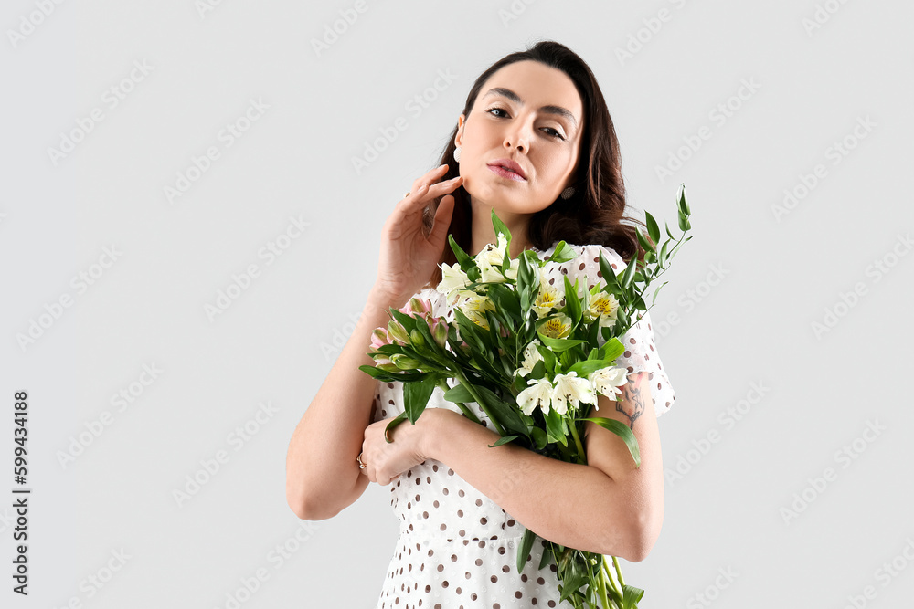 Young woman in dress with alstroemeria flowers on grey background Young woman in dress with alstroemeria flowers on grey background