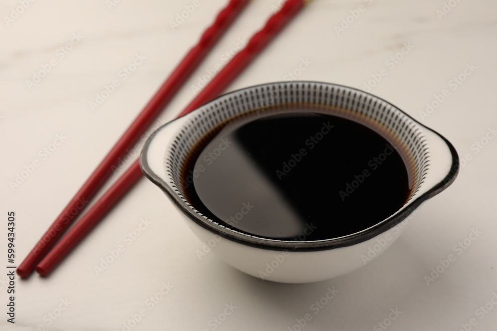 Bowl with soy sauce and chopsticks on white table, closeup Bowl with soy sauce and chopsticks on white table, closeup