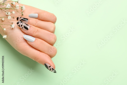 Woman with press-on nails and flowers on green background, closeup