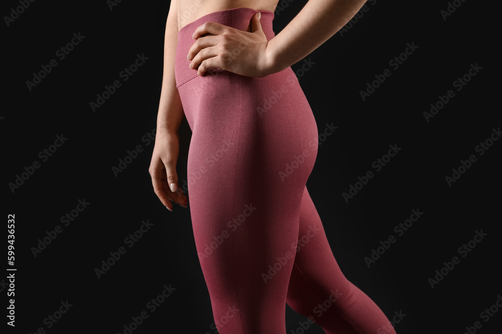 Naklejka premium Sporty young woman in leggings on black background, closeup