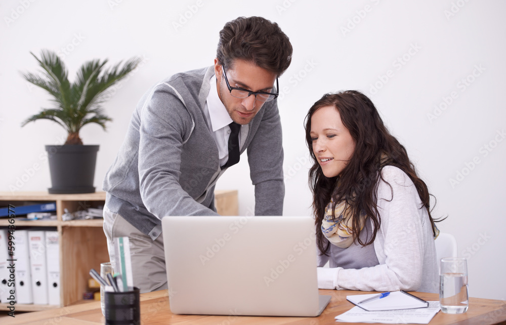 Offering a bit of advice. Two businesspeople working on a laptop in their office. Offering a bit of advice. Two businesspeople working on a laptop in their office.