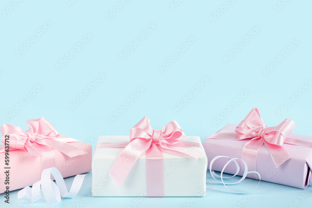 Gift boxes with beautiful bows and serpentine on blue background Gift boxes with beautiful bows and serpentine on blue background
