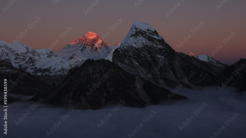 Bright lit Mount Everest surrounded by a sea of fog.