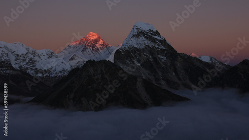 Bright lit Mount Everest surrounded by a sea of fog.
