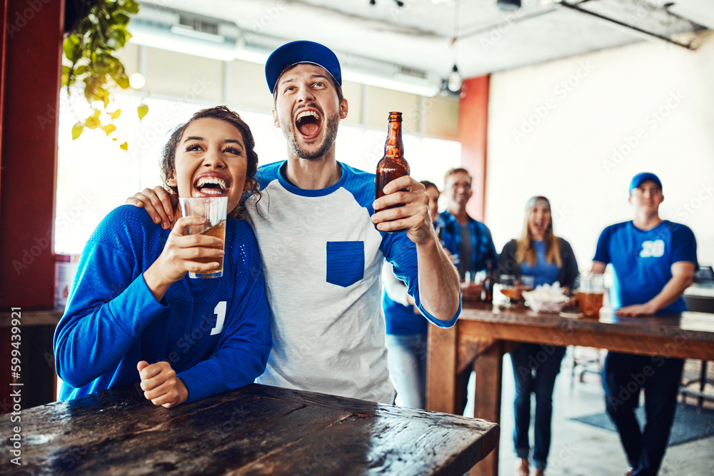 Sports binds you together. a young couple having beer while watching the game in a bar.