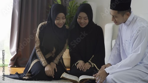 Asian Muslim family reciting surah al-Fatiha passage of the Qur'an, daily prayer at home, a single act of sujud called a sajdah or prostration. Quran holy book is a public item of all Muslim photo