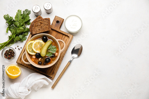 Pot of tasty Hodgepodge soup with bread and sour cream on light background photo