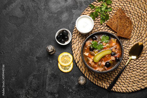 Bowl of tasty Hodgepodge soup with bread and sour cream on dark background photo