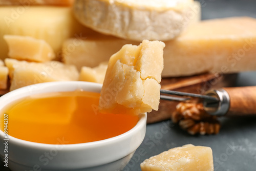 Piece of tasty Parmesan cheese and honey on table, closeup