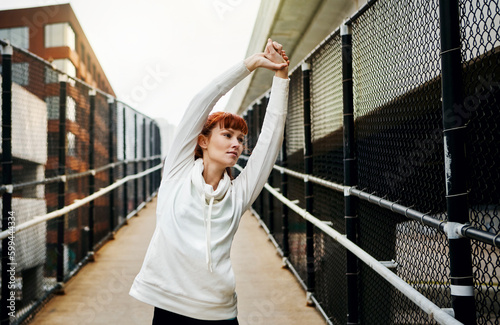 Getting her stretch on. an attractive young woman stretching before her run in the city.