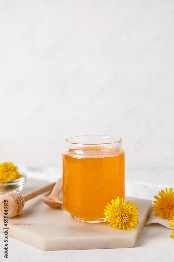 Board with jar of dandelion honey on white table Board with jar of dandelion honey on white table