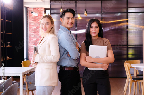 business team standing smiling and holding a laptop. © krongthip