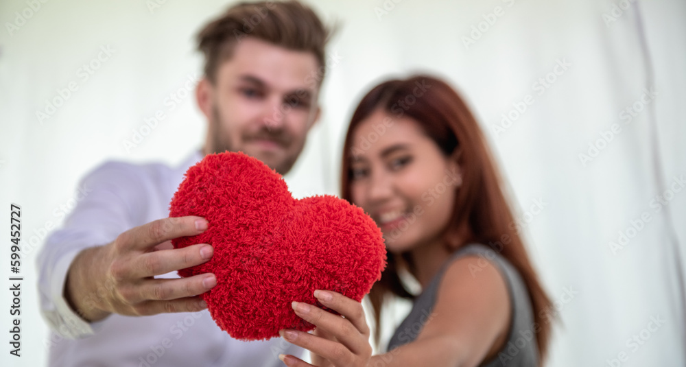 Lover couple show red heart pillow in hands for romantic date at valentine. Two lover holding red pillow symbol for show love. happy in love relaxing looking in eye smiling valentine day Lover couple show red heart pillow in hands for romantic date at valentine. Two lover holding red pillow symbol for show love. happy in love relaxing looking in eye smiling valentine day