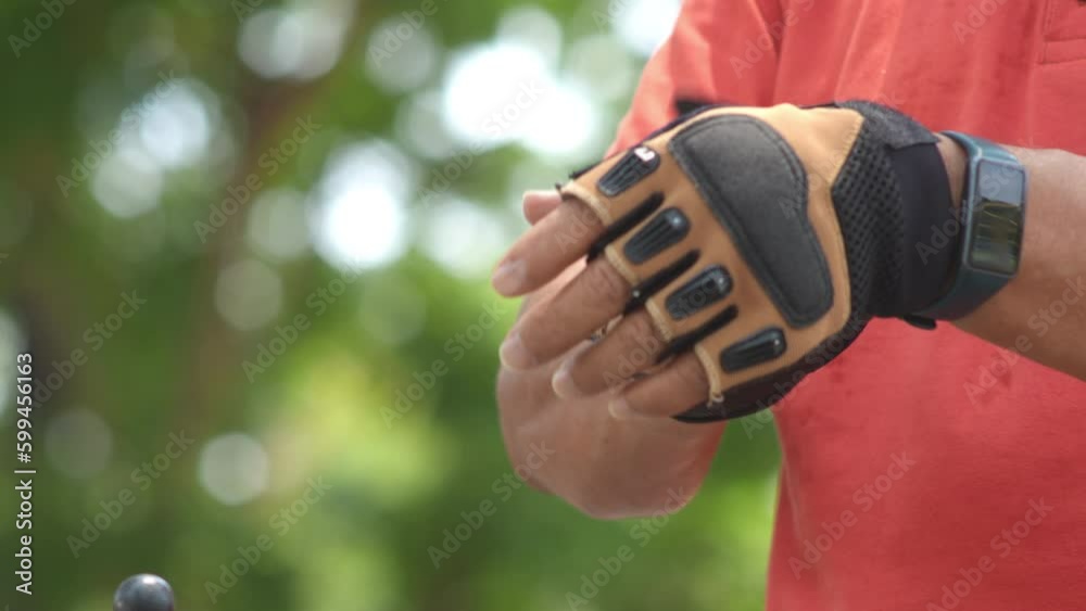 Close up Asian Senior Man hand wearing bicycle gloves before riding on bicycle in park outdoor. Close up Asian Senior Man hand wearing bicycle gloves before riding on bicycle in park outdoor.