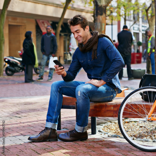 Enjoying the urban lifestyle. a man using his cellphone while taking a break in the city with his bicycle beside him.