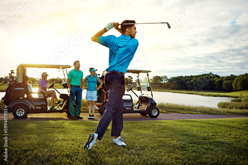 In total charge of his swing. a man playing a round of golf with his friends.