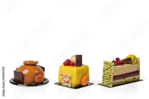 A row of three small, fancy, French, decorated cakes isolated on a white background