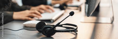 Panorama focus headset on call center workspace desk with blur background of operator team or telesales representative engage in providing client with customer support service or making sales. Prodigy photo