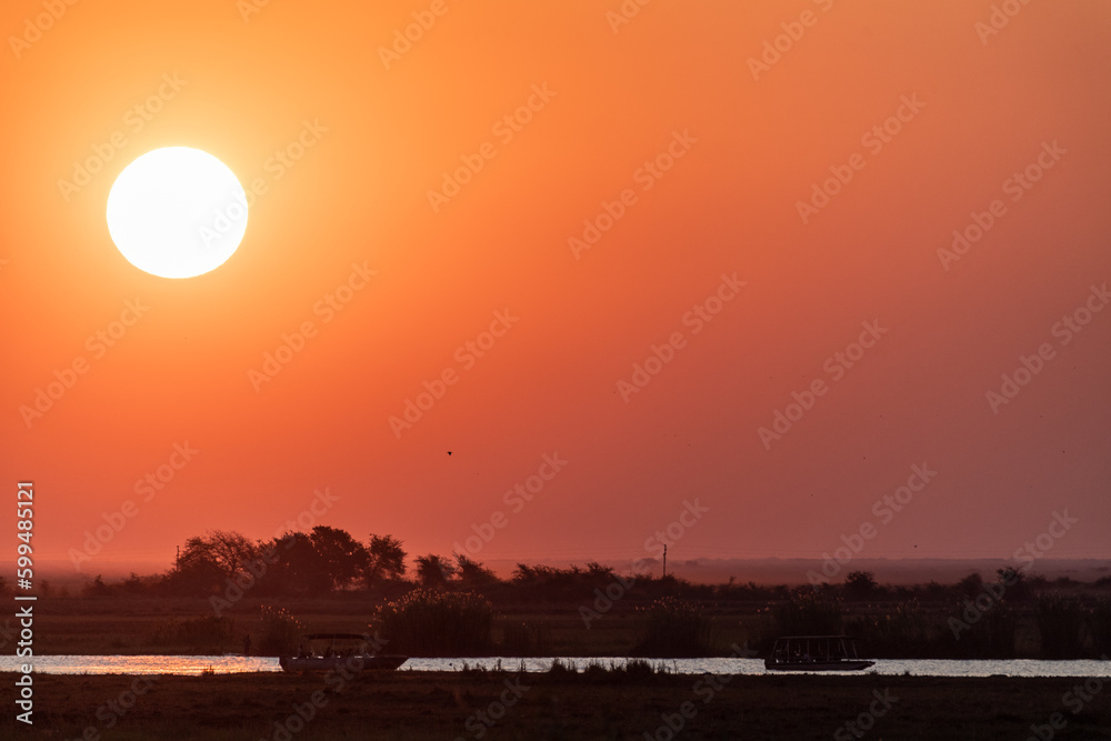 Telephoto shot of the setting sun over the chobe river on a bright winter afternoon in Botswana. Telephoto shot of the setting sun over the chobe river on a bright winter afternoon in Botswana.