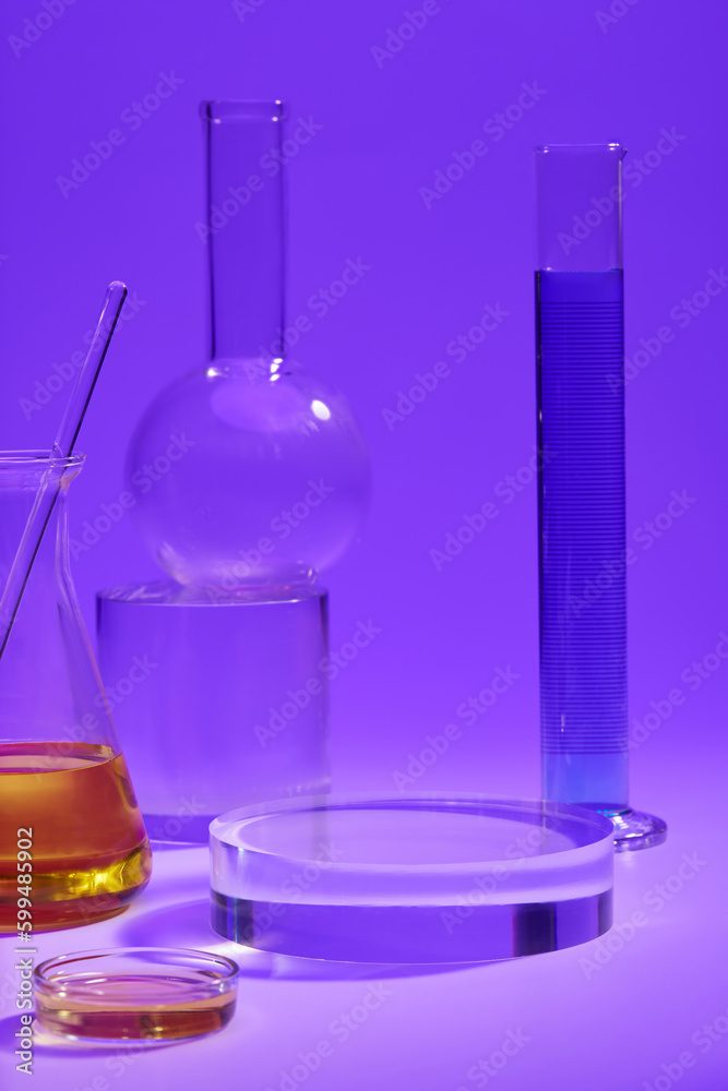 Measuring cylinder of blue fluid, conical flask and petri dish of orange fluid arranged with a round transparent podium. Laboratory concept Measuring cylinder of blue fluid, conical flask and petri dish of orange fluid arranged with a round transparent podium. Laboratory concept