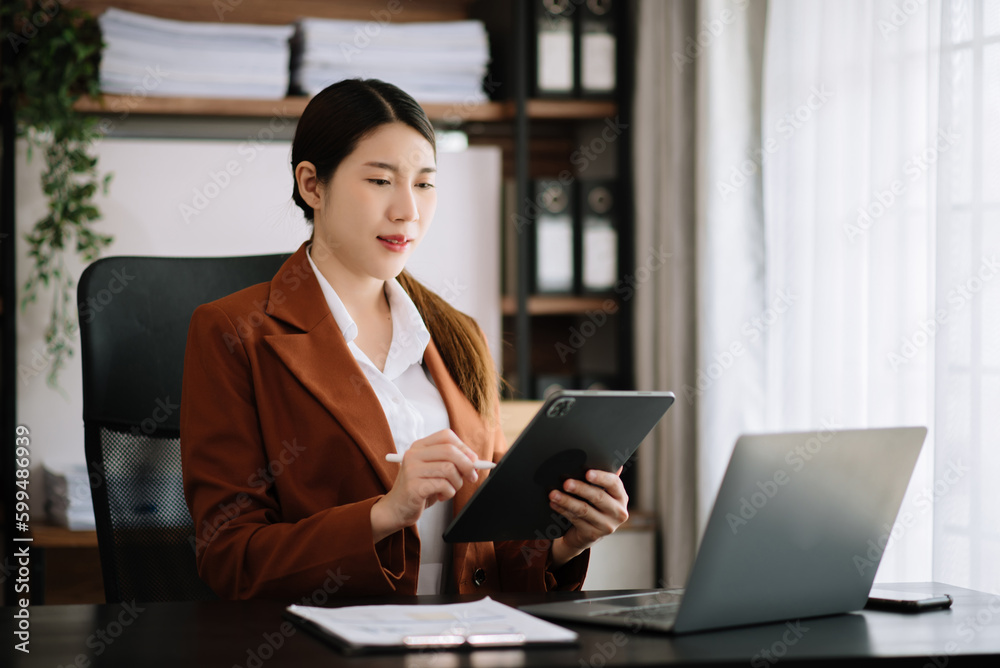 Asian businesswoman working in the office with working notepad, tablet and laptop documents . Asian businesswoman working in the office with working notepad, tablet and laptop documents .