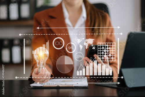 Businesswoman holding and putting lightbulb on coins stack on table for saving energy and money concept.Idea saving energy and finance concept .