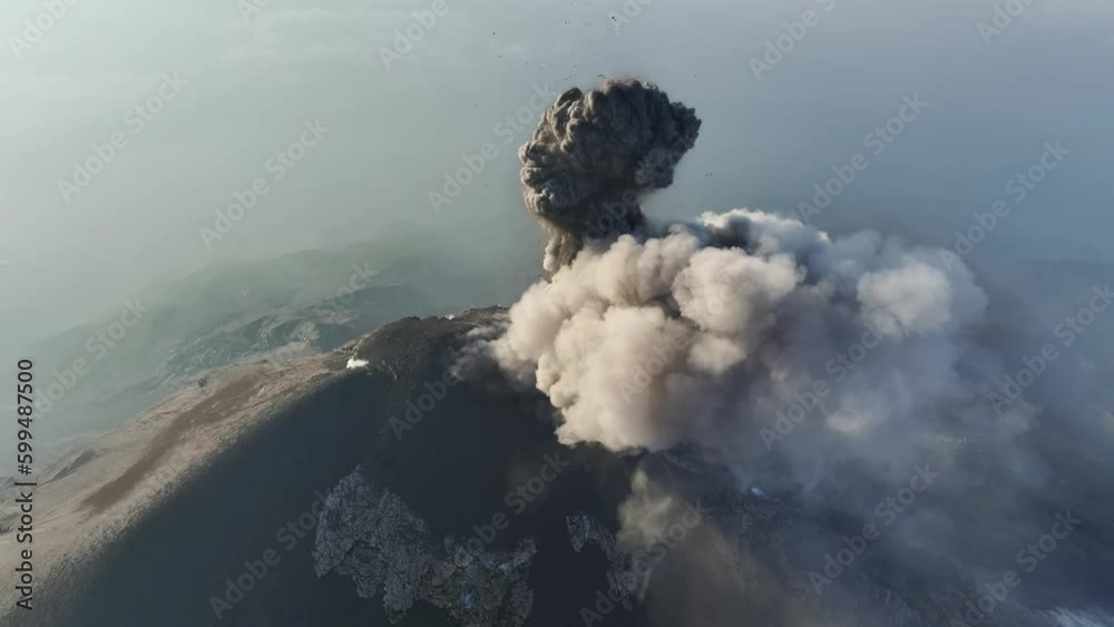 Aerial view of the volcano Fuego in Guatemala as it erupts spewing ash and smoke into the sky. Drone video flying backwards of volcano erupting.