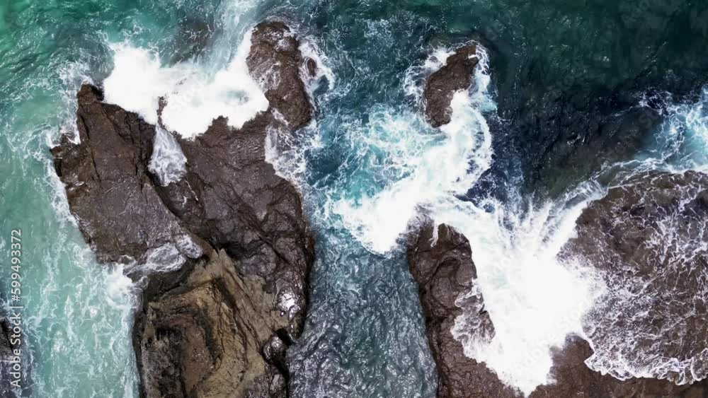 Aerial top down shot of waves crashing on a rocks on the beach Aerial top down shot of waves crashing on a rocks on the beach