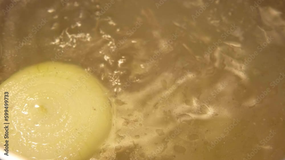 Onion boiled in a thick broth. Clear Soup boiling in a saucepan. Preparing Bouillon. Cooking Bone broth making in a steel pot. Paleo diet. Fresh Vegetables broth in a kitchen Close-up. Selective focus Onion boiled in a thick broth. Clear Soup boiling in a saucepan. Preparing Bouillon. Cooking Bone broth making in a steel pot. Paleo diet. Fresh Vegetables broth in a kitchen Close-up. Selective focus