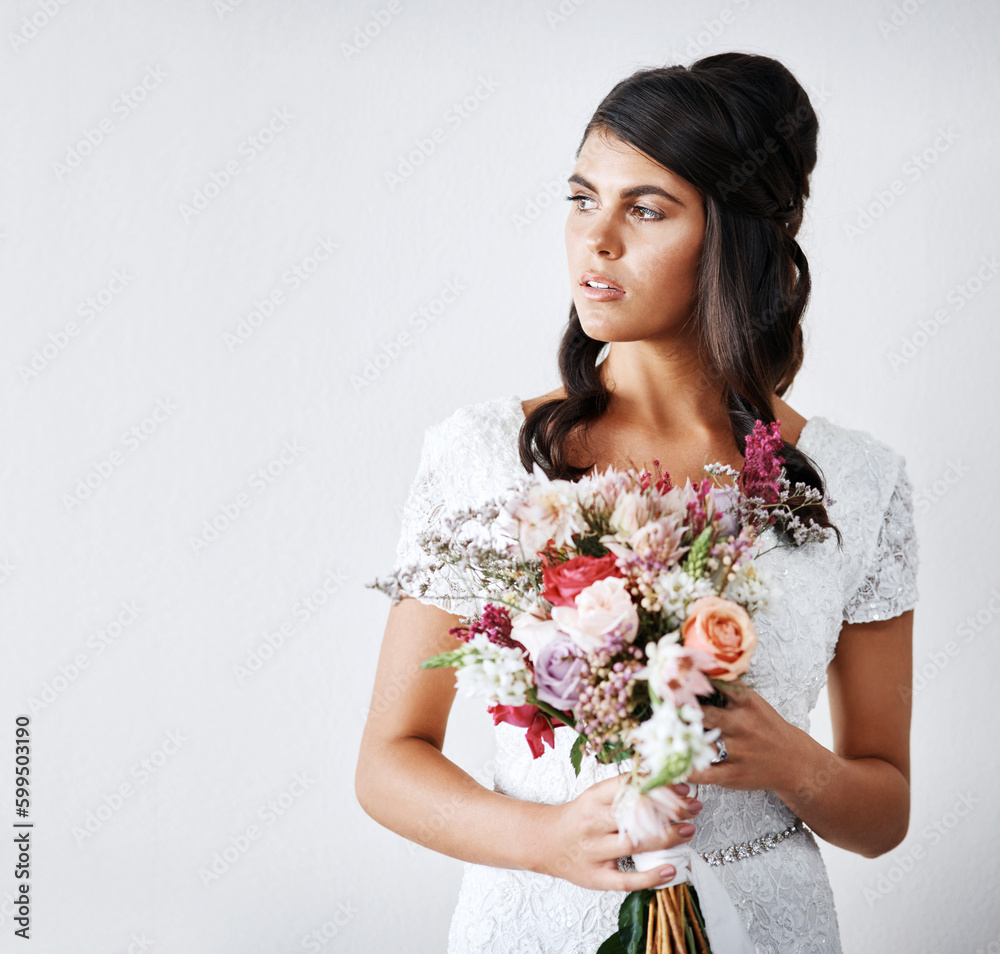 The day has finally arrived. Studio portrait of a young bride holding a bunch of flowers against a gray background. The day has finally arrived. Studio portrait of a young bride holding a bunch of flowers against a gray background.