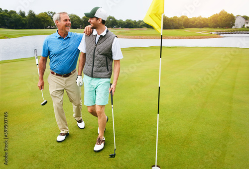 We should do this again. a senior man and his adult son playing golf.