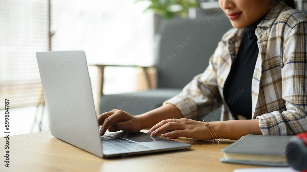 Cropped image of smiling creative woman using laptop, working on design project at home Cropped image of smiling creative woman using laptop, working on design project at home