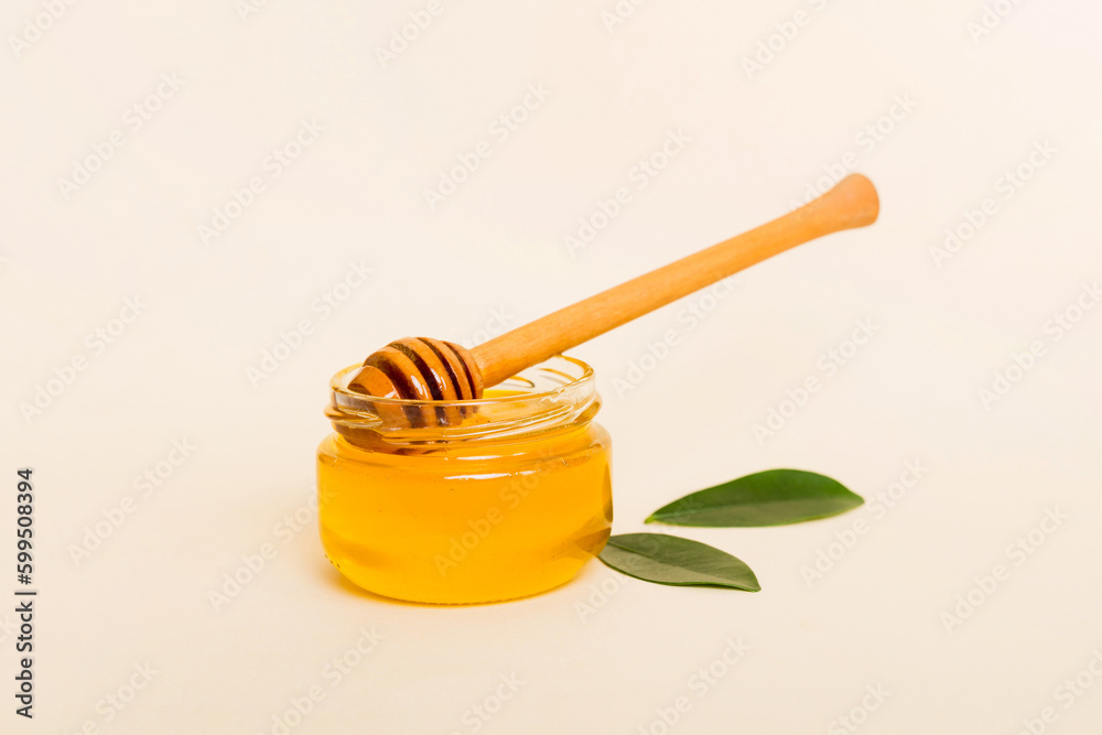 Honey in jar with leaves and honey dipper on colored background top view with copy text Honey in jar with leaves and honey dipper on colored background top view with copy text