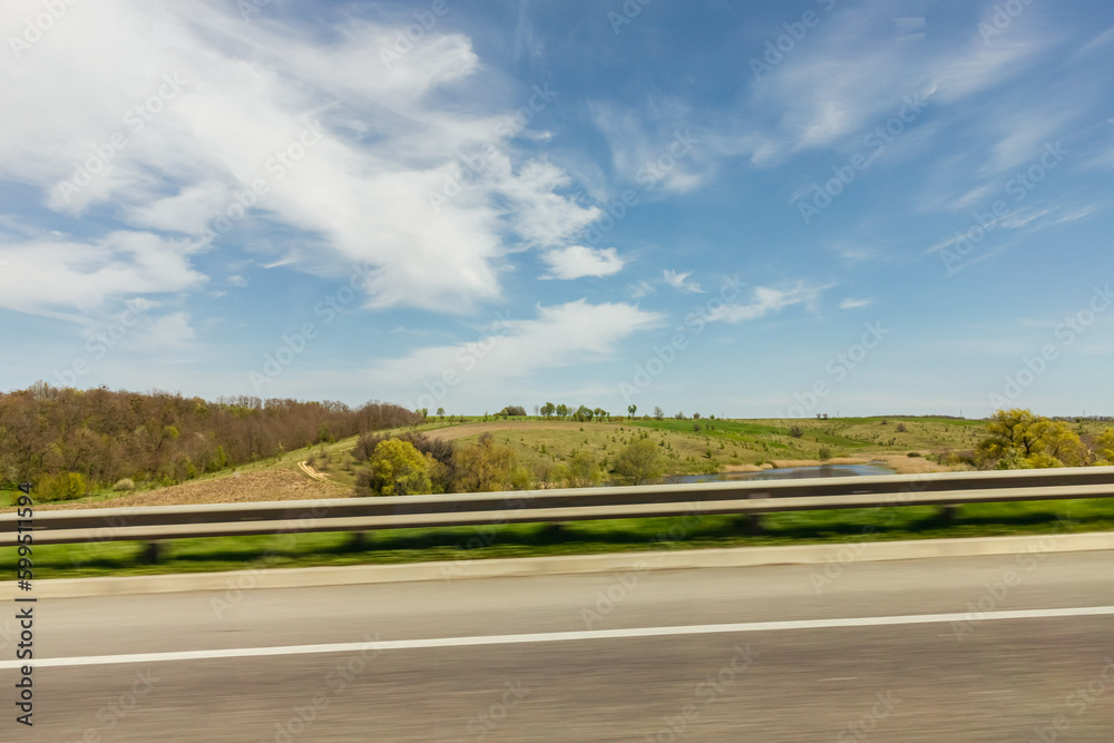 View from the car window. Landscapes of Ukraine. Sunny day. Photo at speed. Green trees on the background of the blue sky. Surrounding scenery.