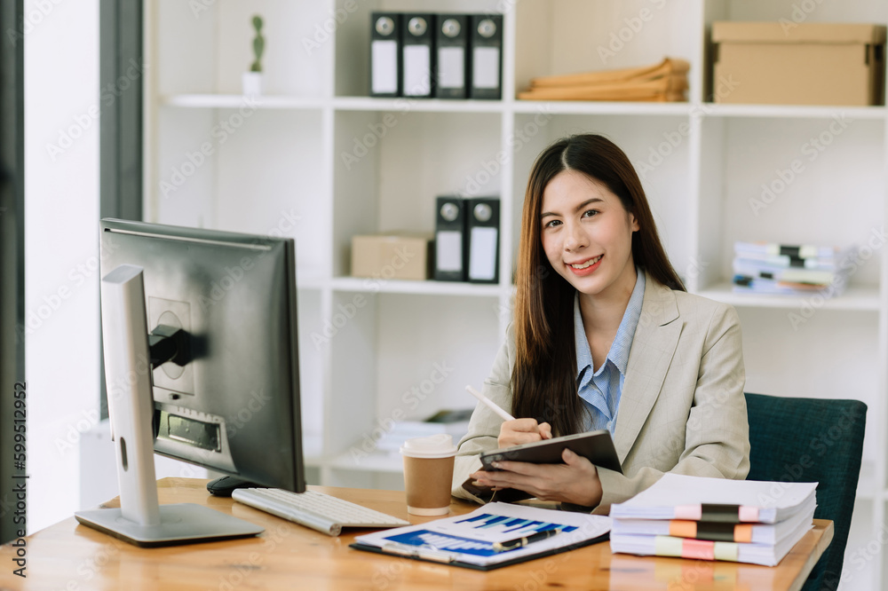 Asian woman using laptop and tablet while sitting at her working place. Concentrated at work.. Asian woman using laptop and tablet while sitting at her working place. Concentrated at work..