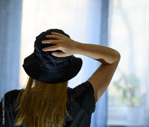 Kobieta w kapeluszu z ręką na głowie 