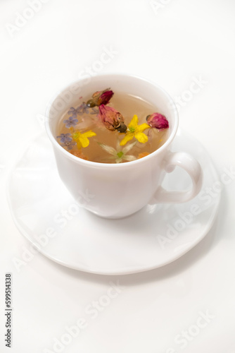 A white cup with fragrant herbal tea and flowers is the perfect choice for health and wellness. Tea time. Relaxing with herbal tea, white background, top view, vertical