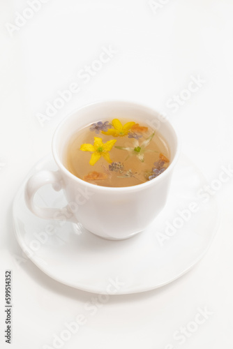 A white cup with fragrant herbal tea and flowers is the perfect choice for health and wellness. Tea time. Relaxing with herbal tea, white background, top view, vertical